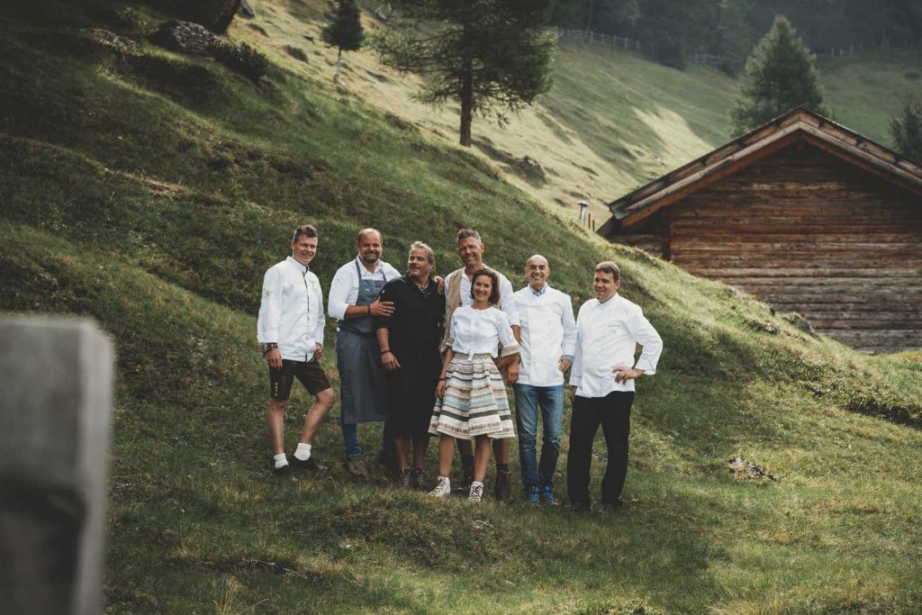Die fünf Südtiroler Spitzenköche Reimund Brunner, Othmar Raich, Walter Weger, (v. l.) sowie Luis Haller und Gerhard Wieser (v. r.) gemeinsam mit ihren Gastgebern Helli und Nadia Gufler (m.) auf der Gompm Alm in Schenna. 